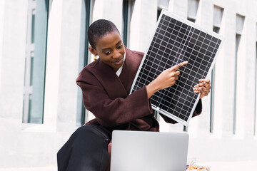Businesswoman pointing on solar panel and using laptop