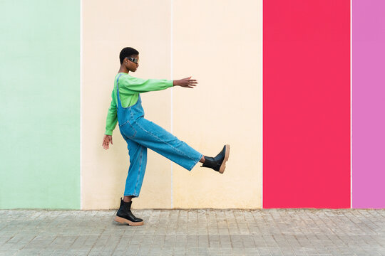 Woman wearing smart glasses gesturing in front of multi colored wall