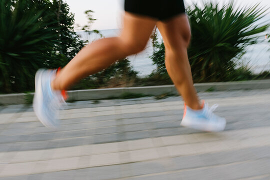 Woman wearing white shoes running on footpath