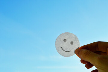 Smiley from white paper on blue sky background. World Day of Peace. Day Against Humiliation....