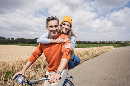 Happy loving couple enjoying bicycle ride together on sunny day