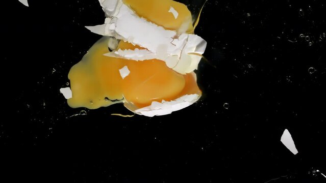 4K - Egg falls and breaks onto glass. Slow-mo directly above camera