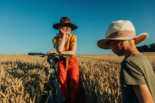 Mother watching son standing next to bicycle in wheat field