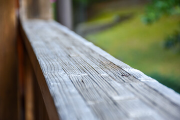 Wooden railing on the terrace outside. Detail on wood. Green landscape in the background