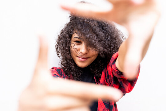 Smiling woman gesturing finger frame in front of wall