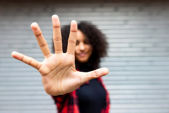 Woman showing stop sign gesture in front of shutter