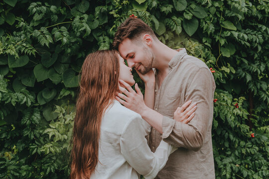 Smiling couple kissing in front of plants in garden