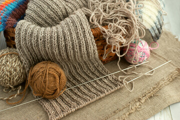 Knitted scarf and yarn in a wicker basket. Knitting needles and yarn for knitting a warm scarf....