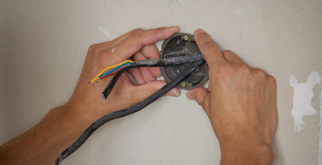 an electrician puts sockets in a plasterboard wall. .
