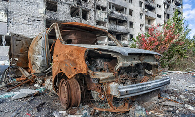 burnt blown up car against the background of a destroyed house in Ukraine