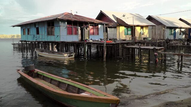 A wooden boat in front of colorful stilted houses at the water's edge