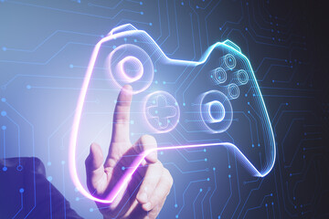 Close up of male hand pointing at creative joystick or gamepad hologram on blurry background. Esport, gaming and fun concept. © Who is Danny