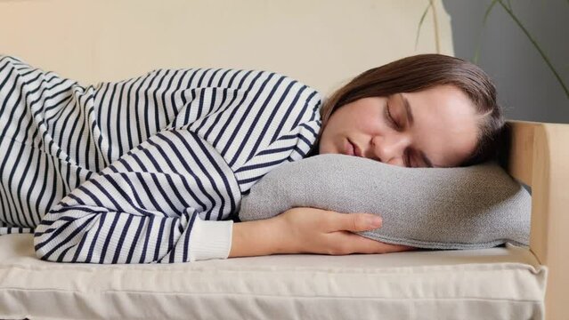 Caucasian woman resting at home on couch, feeling exhausted after work, lacking energy or being overworked too tired and lacking motivation wearing casual striped shirt.