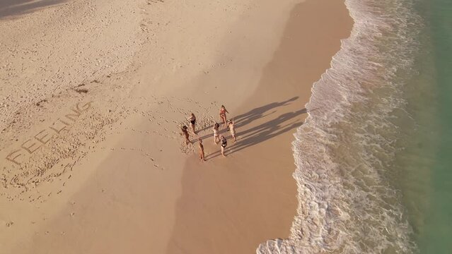 Group of professional dancers having a rehearsal on Maldivian beach at sunset. Aerial Drone shot flyover. High quality 4k footage. High quality 4k footage.
