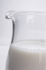 fresh milk in glass jug close-up on white background