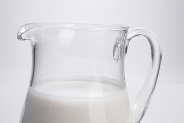 fresh milk in glass jug close-up on white background