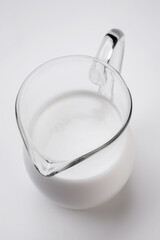 Fototapeta na wymiar fresh milk in glass jug on white background shot from above