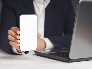 Businessman holding a white blank screen smartphone vertically while sitting at the table