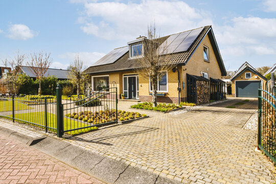 House with solar panels on roof by driveway and open gate