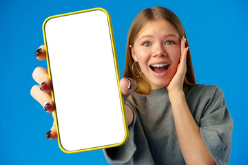 Teen girl showing smartphone screen with copy space over blue background