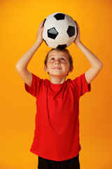 Teen boy soccer player with football ball against yellow background