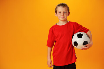 Teen boy soccer player with football ball against yellow background