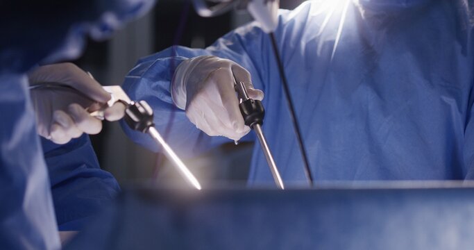 Close up of medics using laparoscopy instruments during surgery. Professional surgeons in surgical suits perform difficult operation using modern equipment. Medical staff save life in medical center.
