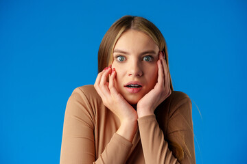 Portrait of worried anxious girl over blue background in studio - obrazy, fototapety, plakaty