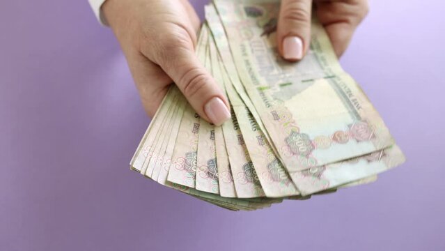 Woman counting AED dirhams in hands, closeup