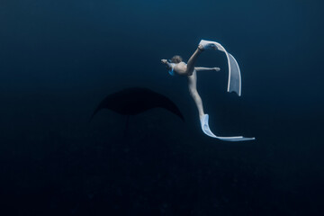 Obraz na płótnie Canvas Woman underwater with manta ray. Freediving with manta rays on deep ocean