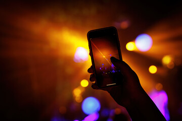 Silhouette of hand with smartphone at a music concert.