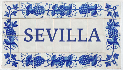 Fototapeta premium Sevilla (Seville in Spanish) on Frame of Azulejos (name of Spanish tiles) with blue bunches of grapes