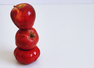 Three ripe red apples stacked vertically on a white background, minimal composition with copy space.