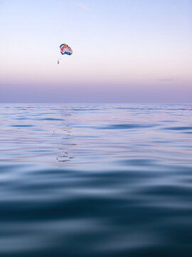 People parachuting during sunset above calm ocean