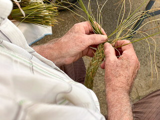 Male hands close up working on basketry with esparto grass