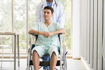 Nurse caring male patient with carefully on wheelchair at hospital. Female assistant taking care male patient on wheelchair at clinic. Healthcare and medical concept