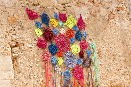 Decoration, consisting of colorful crochet dreamcatchers on the stone wall, on "Costitx en Flor" (Costitx in bloom) Flower Fair, Majorca, Spain