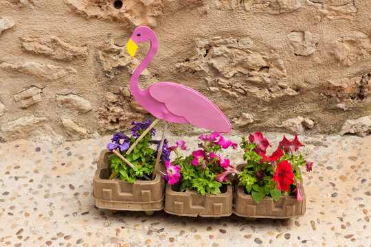Pink flamingo sitting in a flower pot with petunia flowers on "Costitx en Flor" (Costitx in bloom) Flower Fair, Majorca, Spain