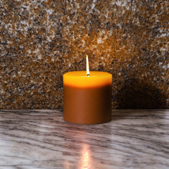 Obraz na płótnie Canvas Orange candle burning on a dark striped marble floor