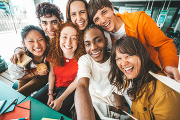 Diverse university students sitting together at table with books and laptop - Happy young people doing group study in high school library - Life style concept with guys and girls in college campus