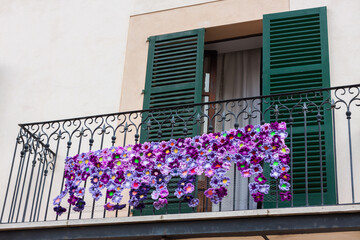 Balcony with green shutters, decorated with violet crochet flowers on 