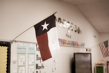 Texas and American flags proudly display in pre-kindergarten classroom near Dallas, modern preschooler class furniture, bulletin board, well organized school supply