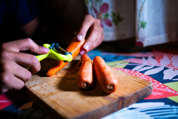 A young boy is peeling carrots.