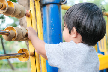 Happy preschool asian boy enjoying with outdoor slider in city park playground