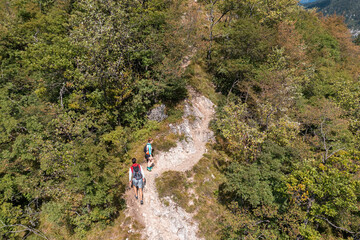 Active couple walking on the hiking trail through the forest, enjoying the view from a mountain...