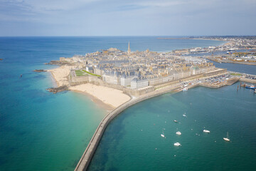 La célèbre cité corsaire de Saint Malo en Bretagne dans le département d'Ille et Vilaine , vue aérienne drone à marée haute avec les plages du sud et le môle des noires.  - obrazy, fototapety, plakaty