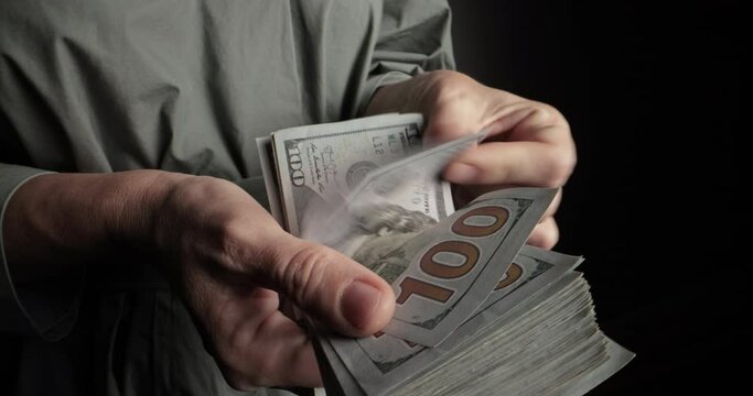 Male hands count dollar bills close up. Guy's hands counting stack of hundred-dollar US banknotes. Successful millionaire counting cash. Concept of abundance, excess of finance, power through money.