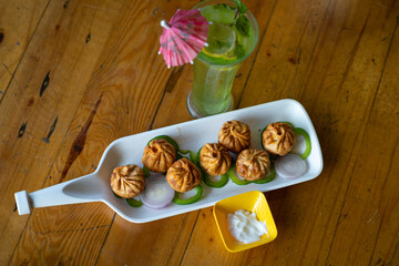 Vegetable fried momo with sauce served and Green apple mojitho mocktail over a rustic wooden background.