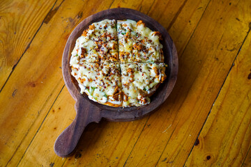 Chicken Pizza on wooden pizza board, isolated over a rustic wooden background.