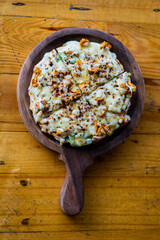 Chicken Pizza on wooden pizza board, isolated over a rustic wooden background.